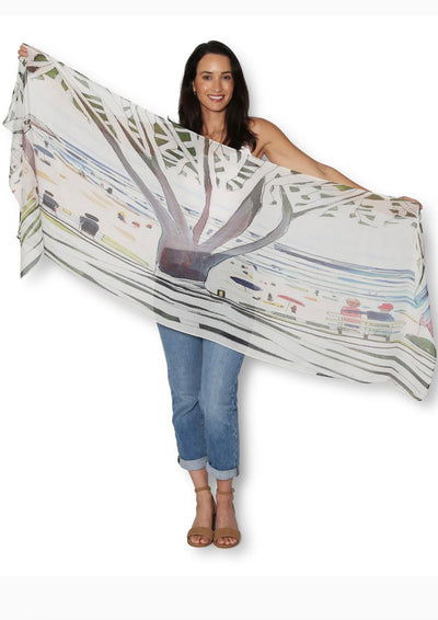 Woman holding a large, patterned scarf on a white background